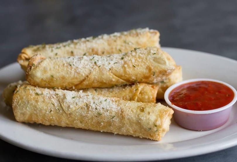 Golden-brown mozzarella sticks, sprinkled with parmesan and herbs, served with a side of marinara sauce.