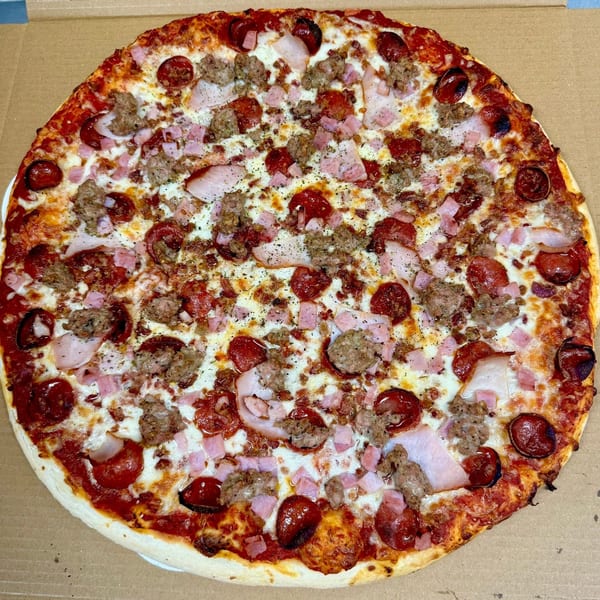 A whole meat lover's pizza with pepperoni, sausage, ham, and bacon in a cardboard box.